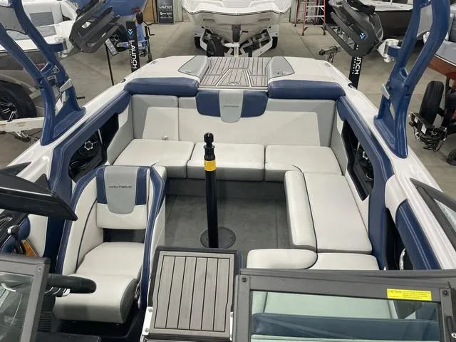 Slide: The Image of 2015 Nautique 200 boat interior with white and blue seating in a showroom. - 8