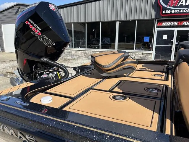 Slide: The Image of 2025 Caymas XS 21 Pro boat with tan deck and powerful engine, parked outside a showroom. - 6