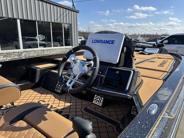 Slide: The Image of 2025 Caymas XS 21 Pro boat interior with Lowrance electronics, steering wheel, and tan seating. - 7