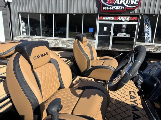Slide: The Image of 2025 Caymas XS 21 Pro boat interior with tan and black seats, displayed at a marine dealership. - 8