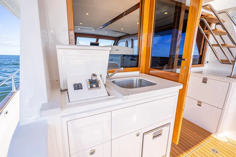 Slide: The Image of 2026 Grand Banks GB 54 yacht deck with sink and wooden accents. - 11