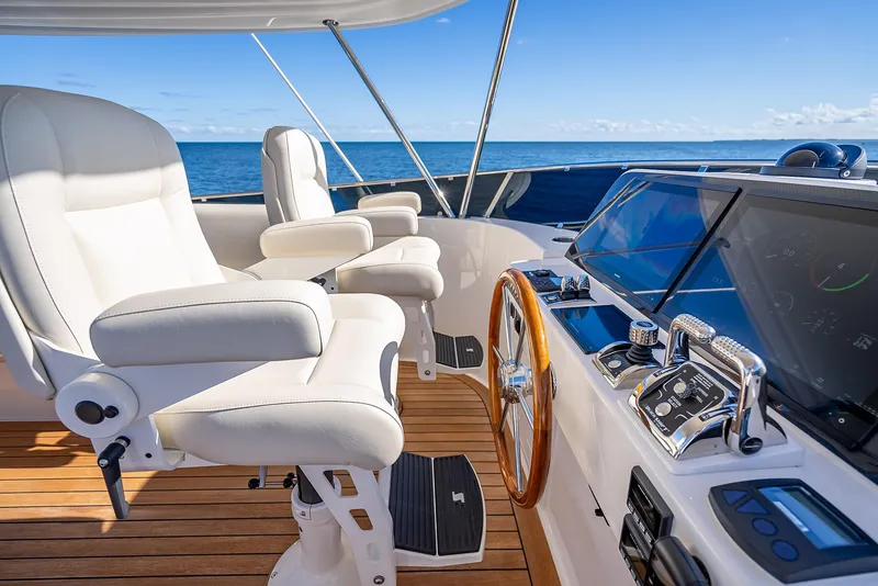 Slide: The Image of Luxurious helm of 2026 Grand Banks GB 54 yacht with white leather seats and wooden steering wheel. - 21