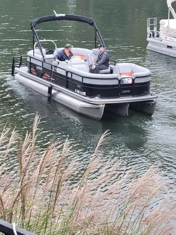 Slide: The Image of 2021 Lowe SS230 Walk Thru pontoon boat on a calm lake with two passengers. - 3