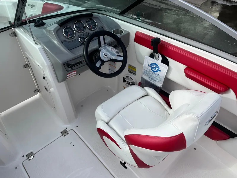 Slide: The Image of 2016 Chaparral 21 H2O boat cockpit with steering wheel and red-trimmed seat. - 8