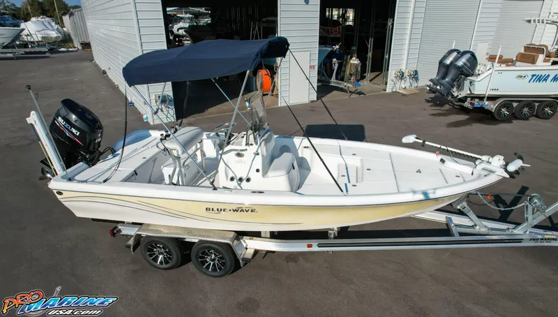 Slide: The Image of 2011 Blue Wave 2200 Pure Bay boat on trailer with canopy, parked outside a storage facility. - 10