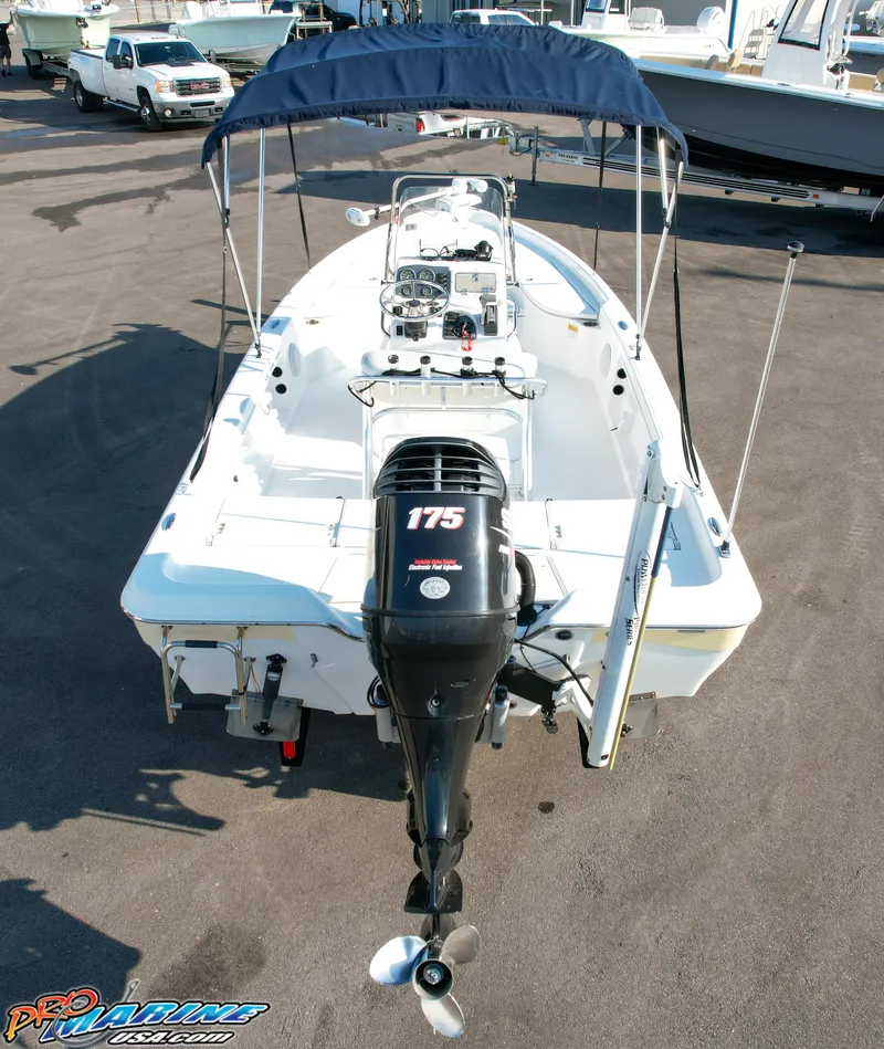 Slide: The Image of 2011 Blue Wave 2200 Pure Bay boat with canopy and 175 HP engine, parked on pavement. - 13