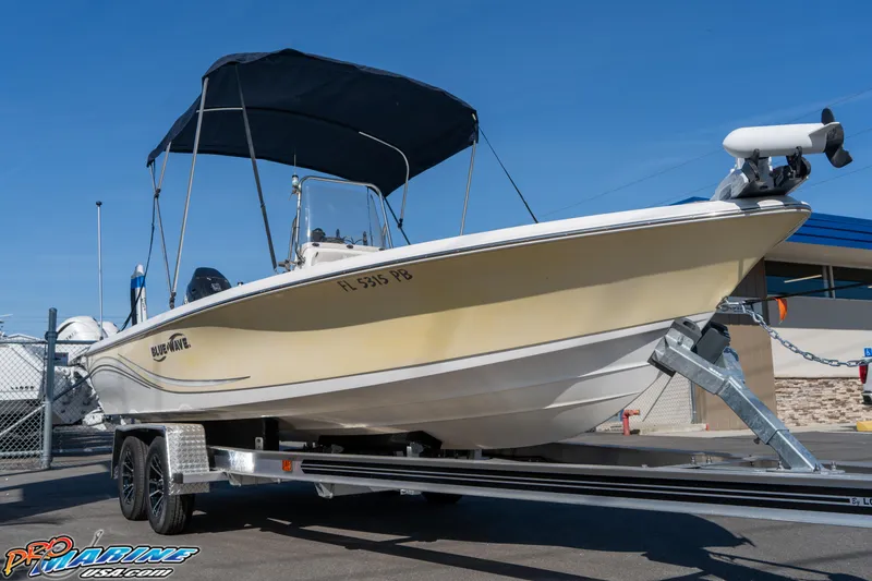Slide: The Image of 2011 Blue Wave 2200 Pure Bay boat on trailer with canopy, parked outdoors. - 7