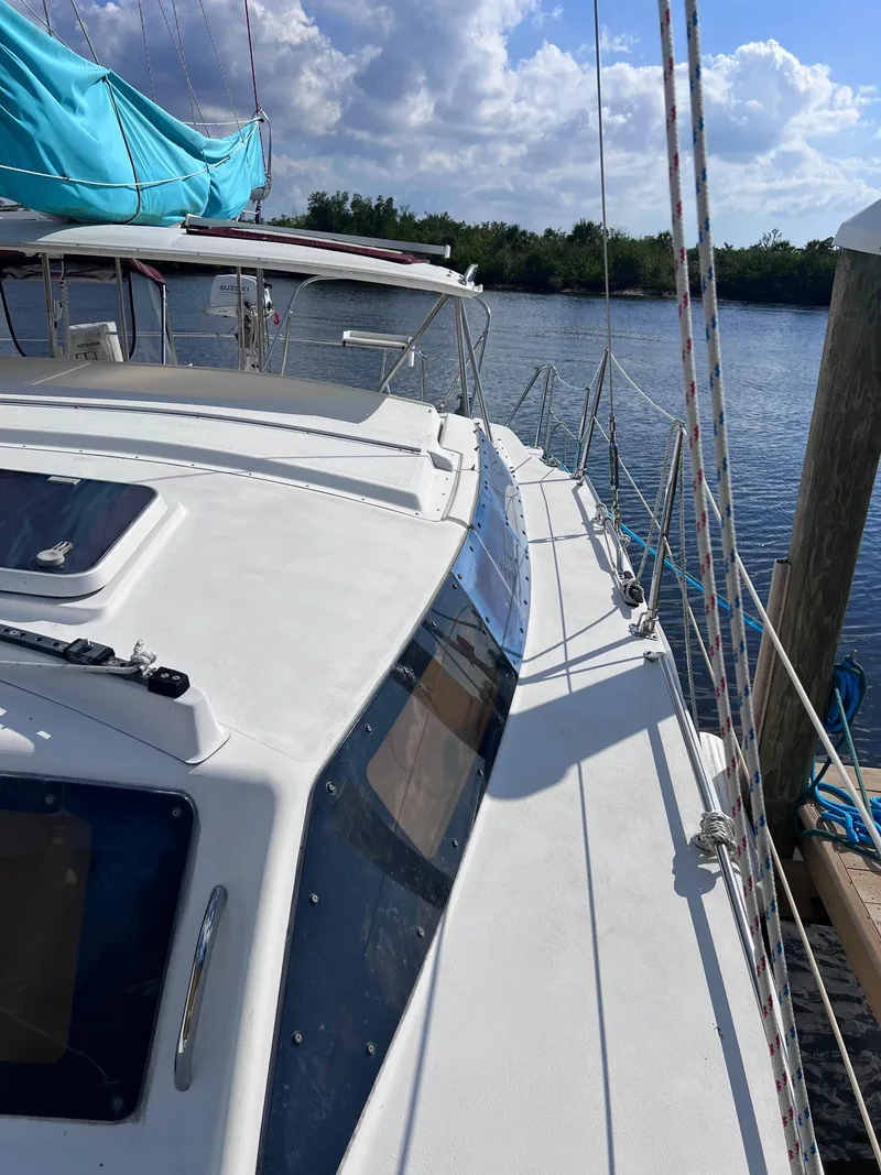 Slide: The Image of Sailboat docked by the water, PDQ 32 Classic, 1994 model, with blue sail cover. - 10