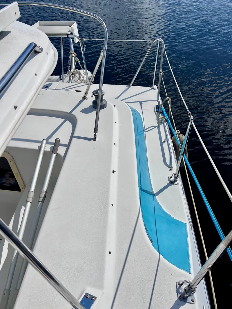 Slide: The Image of 1994 PDQ 32 Classic boat deck with blue accents, docked on calm water. - 11