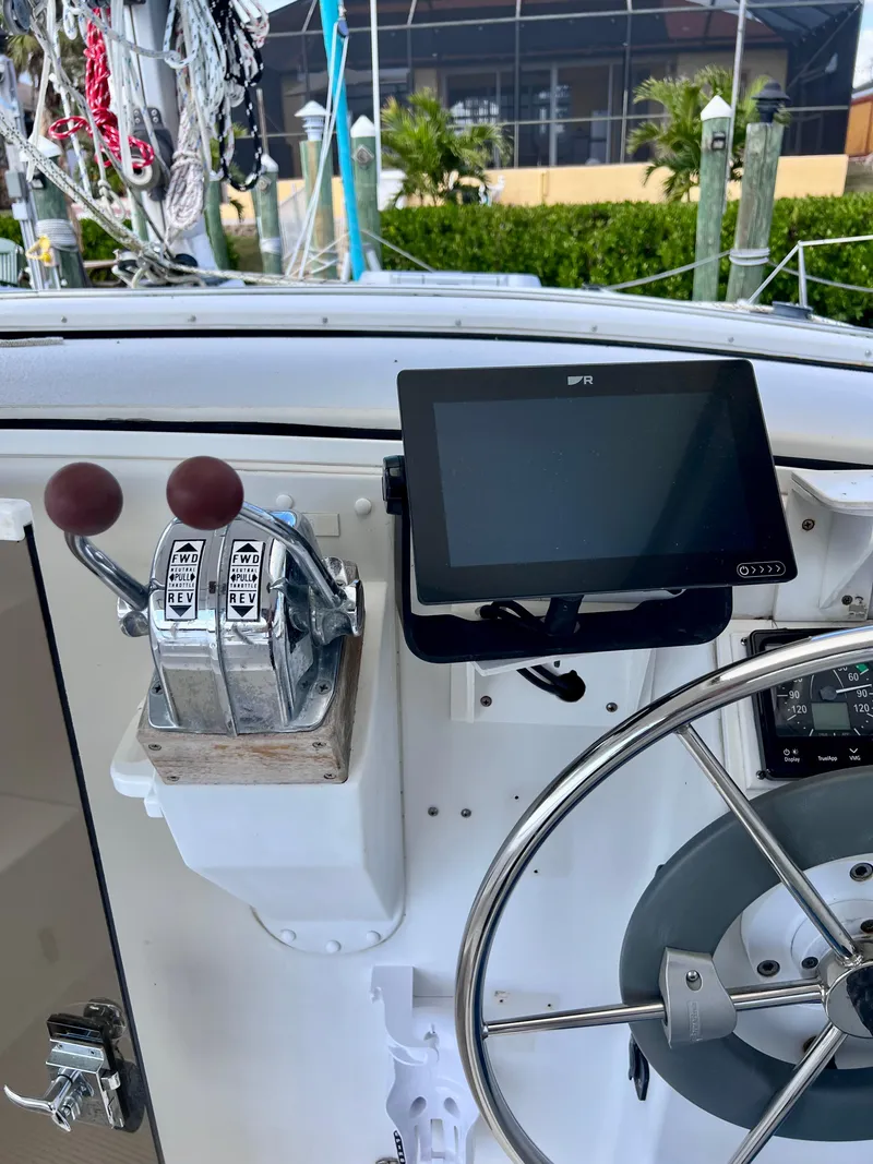 Slide: The Image of Control panel of a 1994 PDQ 32 Classic boat with steering wheel and navigation screen. - 23