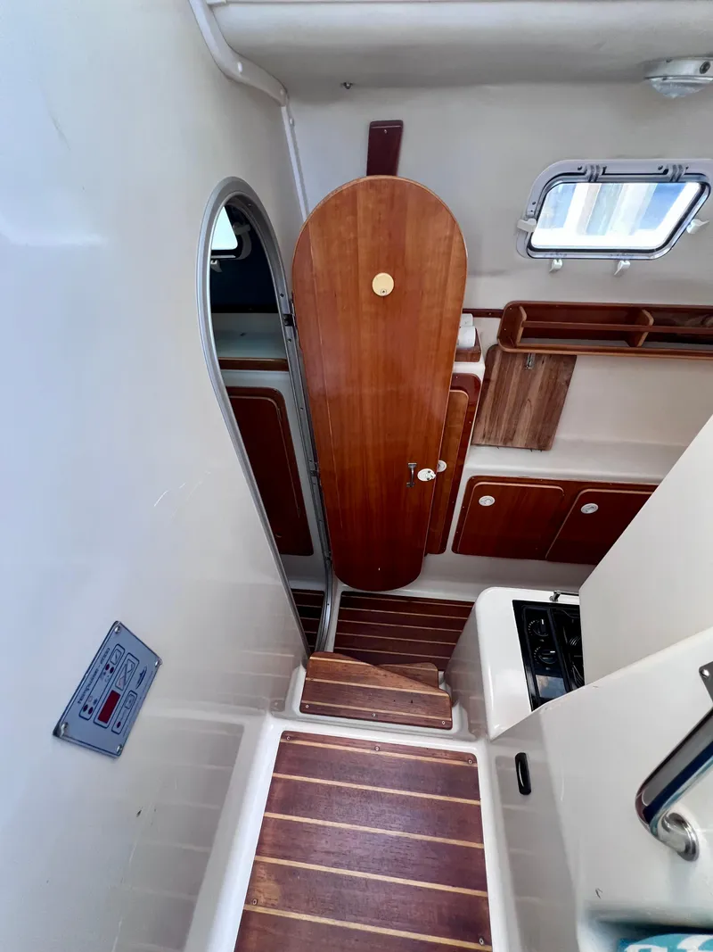 Slide: The Image of Interior of a 1994 PDQ 32 Classic boat, featuring wooden cabinetry and steps. - 31