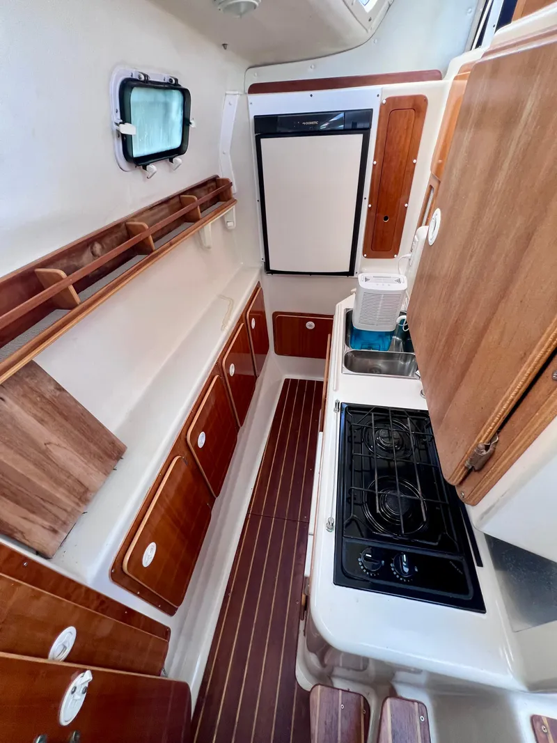 Slide: The Image of 1994 PDQ 32 Classic yacht interior with wooden cabinets, stove, and compact kitchen layout. - 32