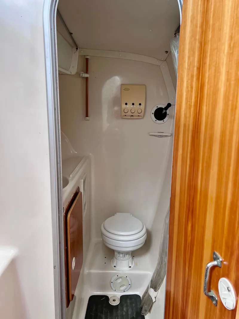 Slide: The Image of Compact bathroom in a 1994 PDQ 32 Classic boat, featuring a toilet and wooden door. - 49