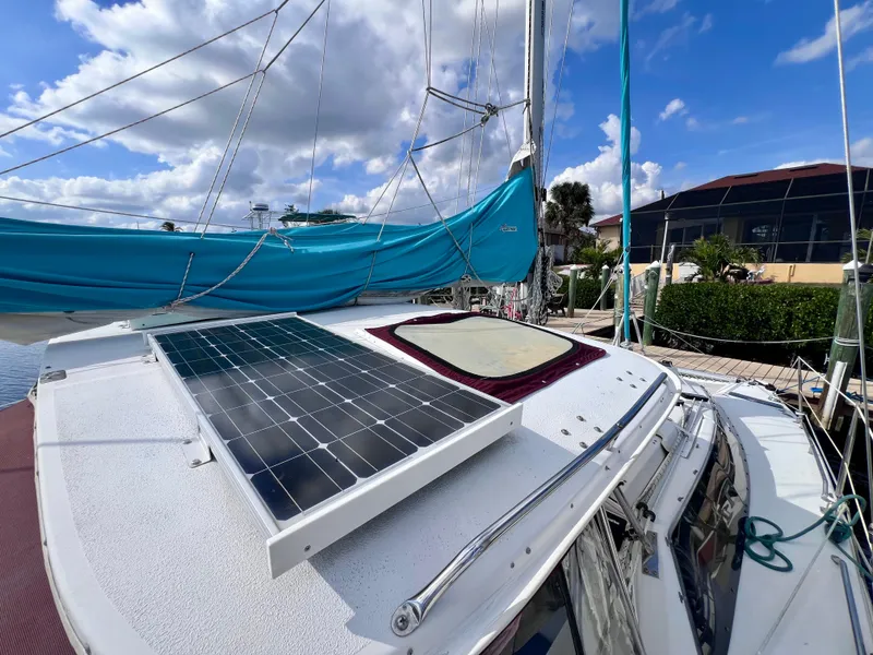 Slide: The Image of 1994 PDQ 32 Classic sailboat with solar panel and blue sail cover, docked under a cloudy sky. - 7
