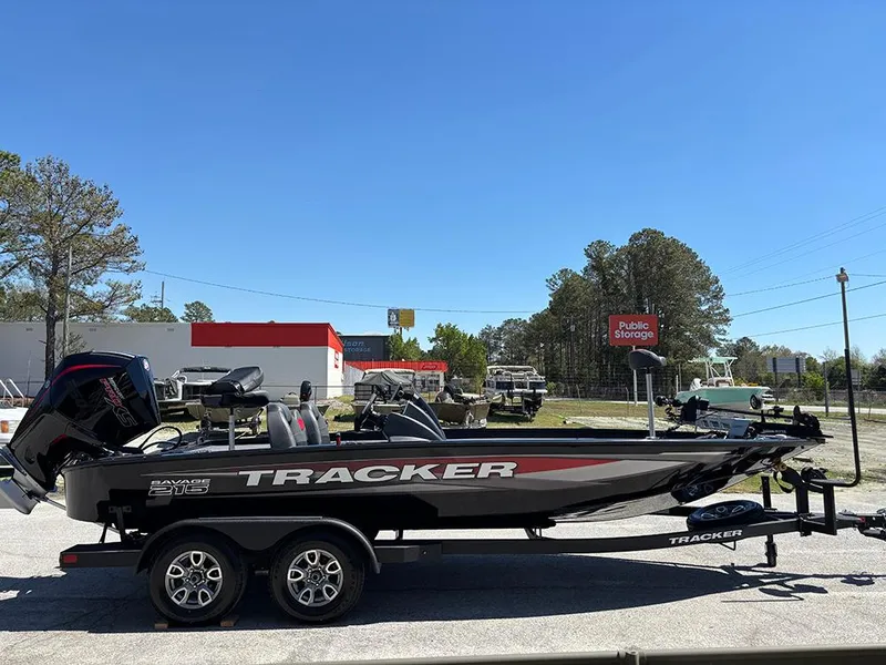 Slide: The Image of 2025 Tracker Savage 215 boat on trailer, parked near storage facility. - 6