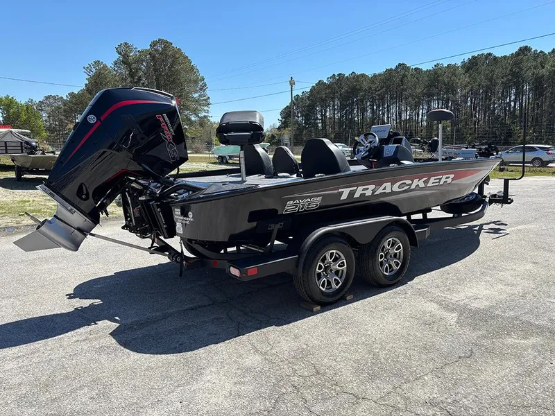 Slide: The Image of 2025 Tracker Savage 215 boat on trailer, parked outdoors, with trees in the background. - 7