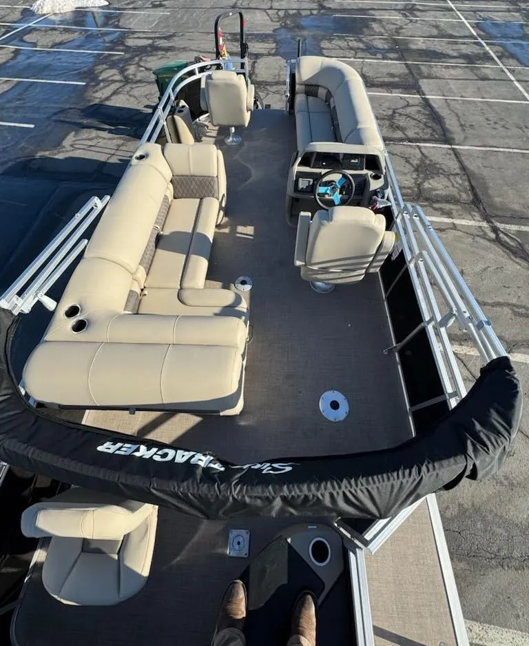 Slide: The Image of 2025 Sun Tracker SportFish 20 DLX pontoon boat with beige seating in a parking lot. - 8