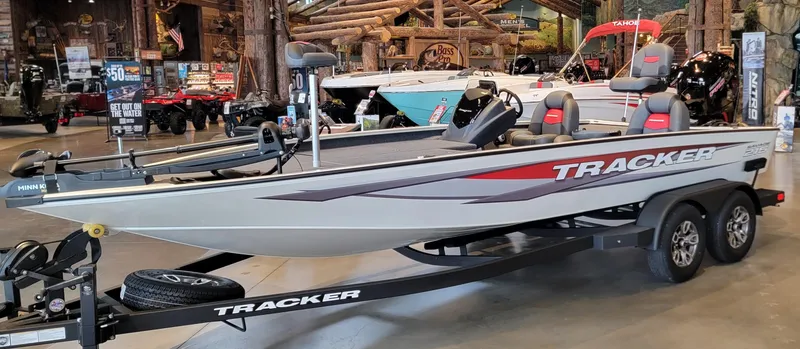 The Image of 2025 Tracker Savage 215 boat on display in showroom, "We Take Trades" sign visible. - 0