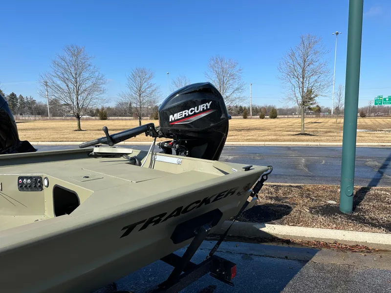 Slide: The Image of 2025 Tracker Grizzly 1654 T Sportsman boat with Mercury outboard motor, parked outdoors. - 3