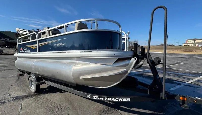 Slide: The Image of 2025 Sun Tracker Bass Buggy 16 XL Select pontoon boat on trailer in parking lot. - 6