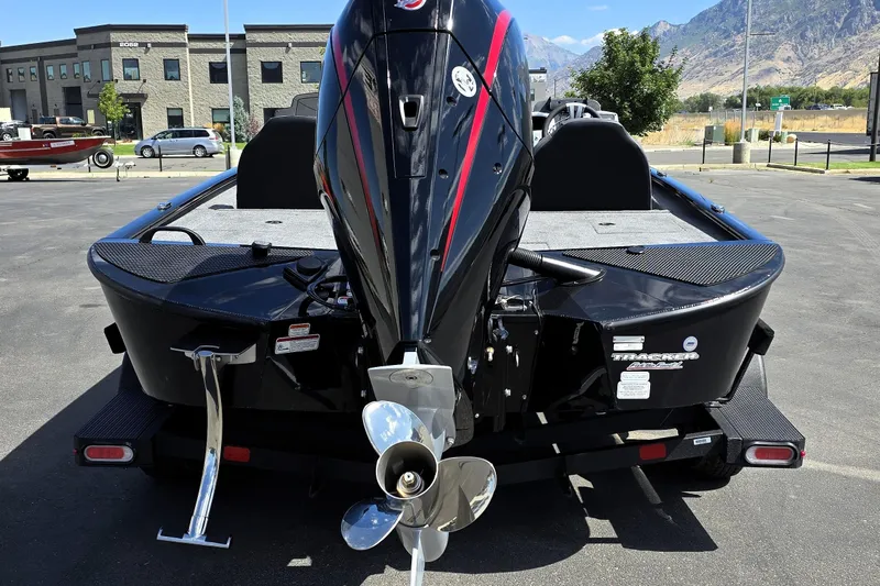 Slide: The Image of 2025 Tracker Savage 215 boat with powerful outboard motor, parked outdoors. - 88