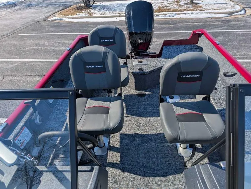 Slide: The Image of 2025 Tracker Pro Guide V-16 WT boat interior with seating and motor, parked on pavement. - 3