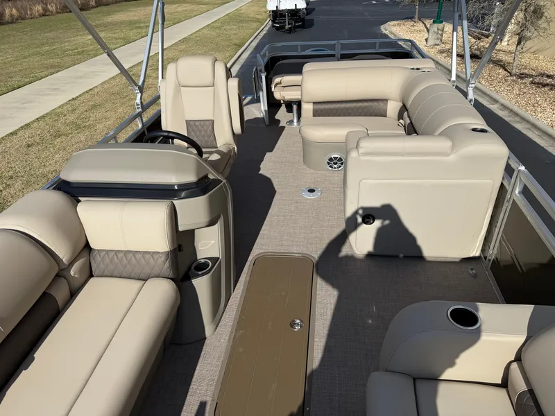 Slide: The Image of 2025 Sun Tracker SportFish 22 XP3 pontoon boat interior with beige seating and steering console. - 2