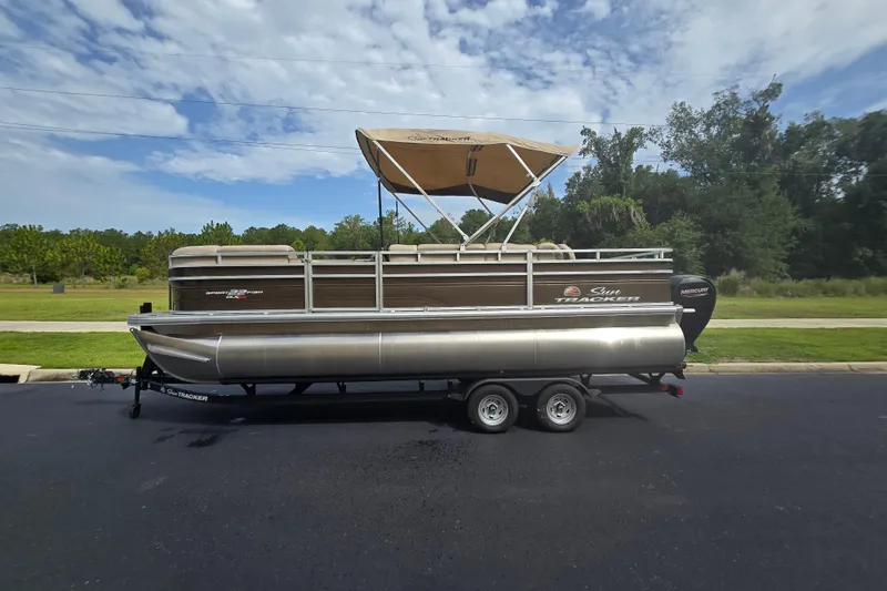 Slide: The Image of 2025 Sun Tracker SportFish 22 XP3 pontoon boat on trailer, parked outdoors. - 80