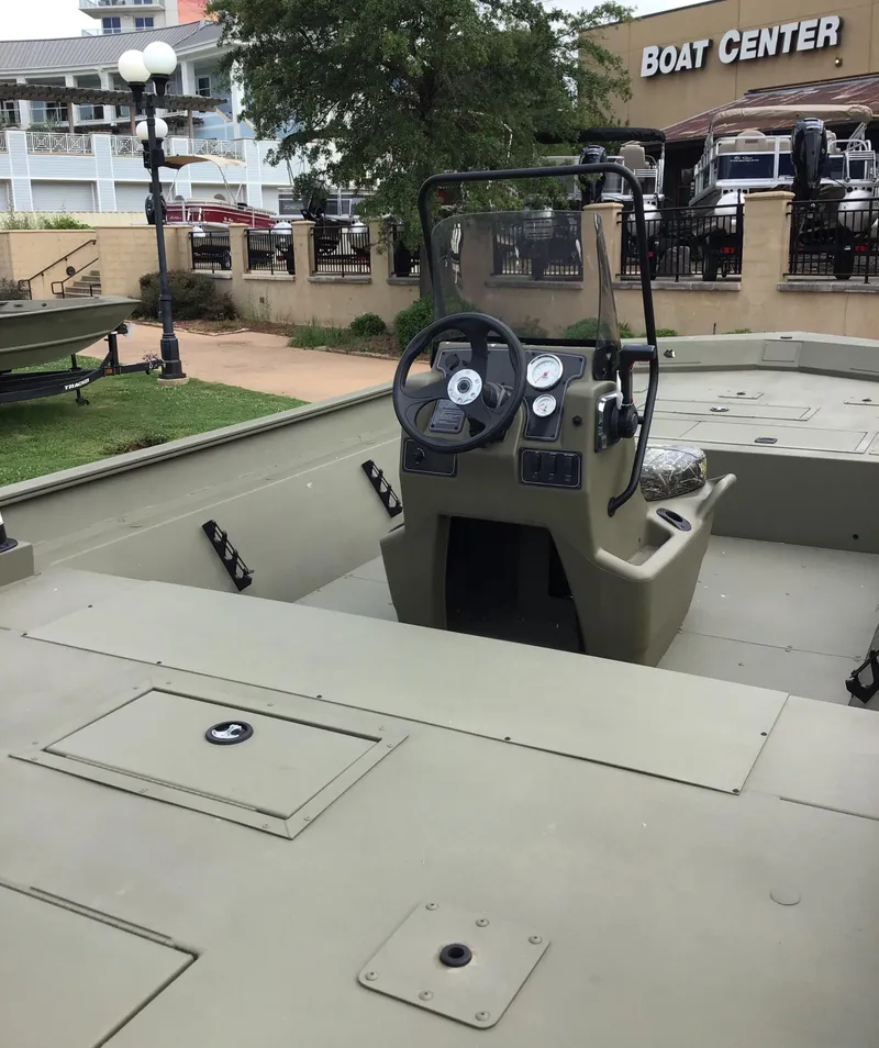 Slide: The Image of 2025 Tracker Grizzly 2072 CC boat at a dealership, featuring a central console and spacious deck. - 2