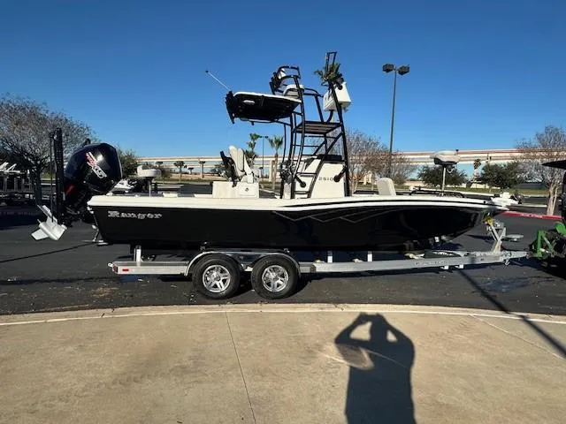 The Image of 2023 Ranger 2510 Bay boat on trailer, parked outdoors under clear blue sky. - 0