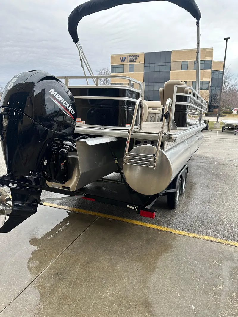 Slide: The Image of 2025 Sun Tracker SportFish 22 XP3 pontoon boat with Mercury engine, parked outdoors. - 3