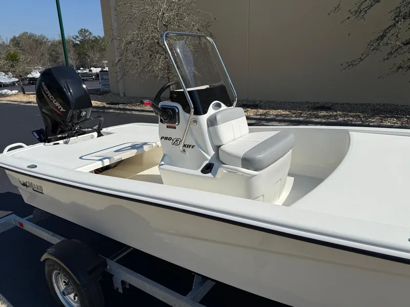 Slide: The Image of 2025 Mako Pro Skiff 13 CC boat on trailer, featuring center console and outboard motor. - 2