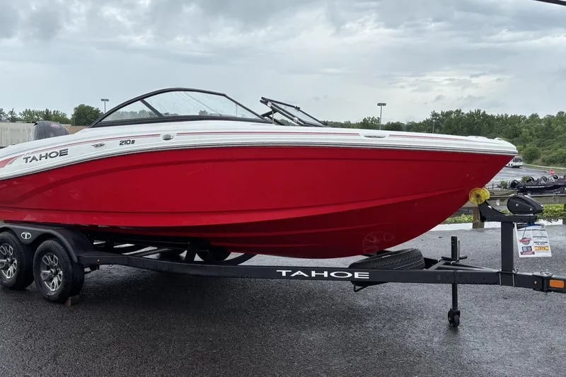 Slide: The Image of 2025 Tahoe 210 S boat in vibrant red on a trailer, parked outdoors. - 1