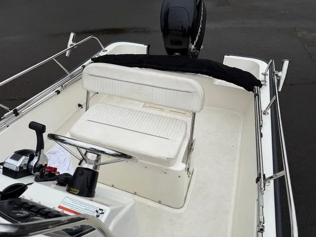 Slide: The Image of 2010 Boston Whaler 170 Montauk boat interior with white seating and steering console. - 6