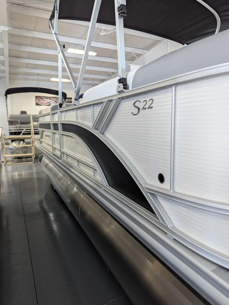 Slide: The Image of 2024 Bennington 22SSR pontoon boat in showroom, side view with sleek design. - 2