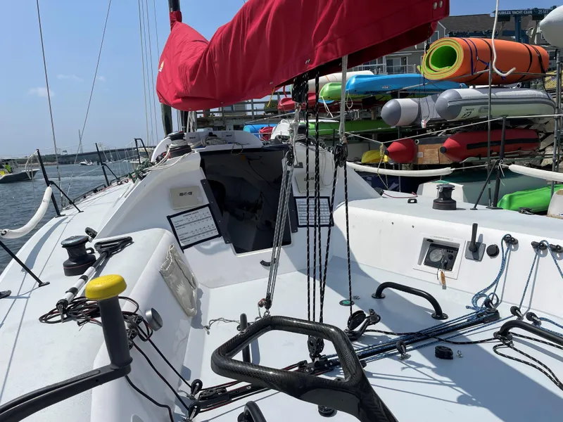 Slide: The Image of Columbia Yacht 32, 2012 model, with red sail, docked near colorful kayaks. - 9