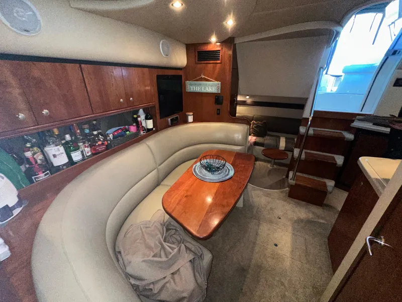 Slide: The Image of 2005 Cruisers Yachts 340 Express interior with curved seating and wooden table. - 5