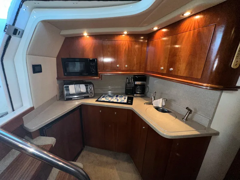 Slide: The Image of 2005 Cruisers Yachts 340 Express kitchen with wood cabinets, microwave, and sink. - 4