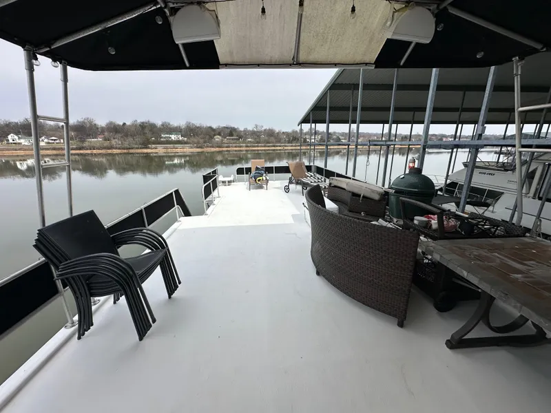 Slide: The Image of 1991 Sumerset 14x60 houseboat deck with chairs and table, overlooking calm waters. - 10
