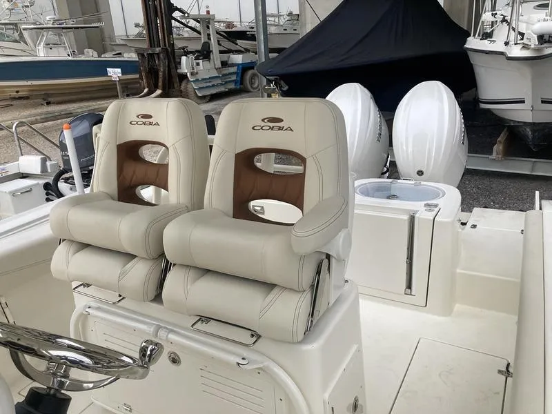 Slide: The Image of 2024 Cobia 262 CC boat with dual seats and twin outboard engines. - 10