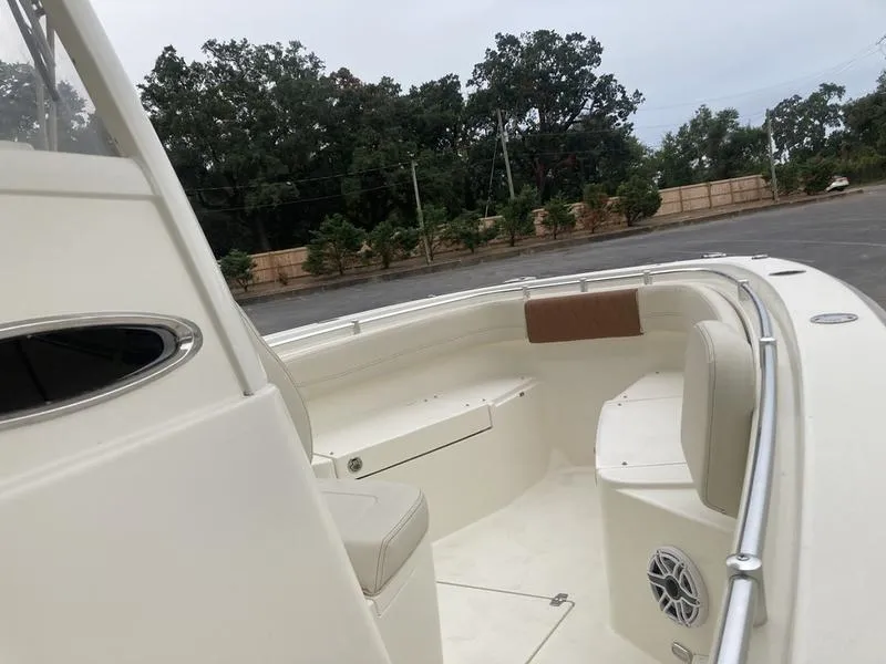 Slide: The Image of 2024 Cobia 262 CC boat interior with seating and speaker, parked outdoors. - 12