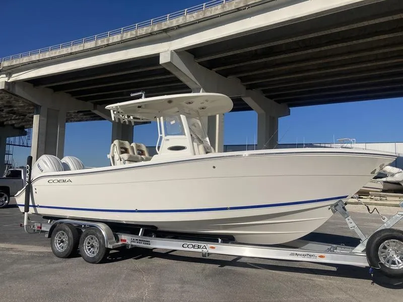 Slide: The Image of 2024 Cobia 262 CC boat on trailer under bridge. - 2