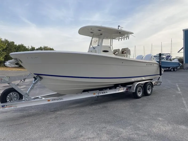 Slide: The Image of 2024 Cobia 262 CC boat on trailer, parked outdoors, side view. - 3
