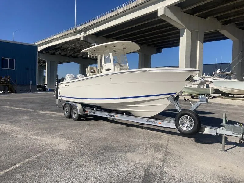 Slide: The Image of 2024 Cobia 262 CC boat on trailer under bridge, sunny day. - 4