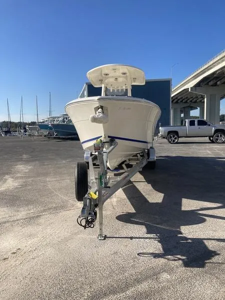Slide: The Image of 2024 Cobia 262 CC boat on trailer, parked near marina under clear blue sky. - 6