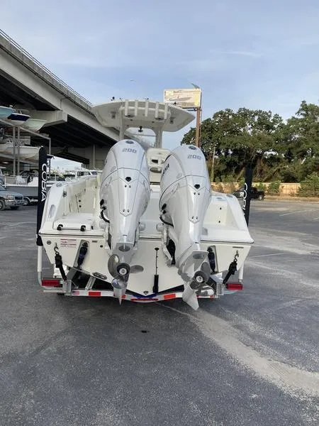 Slide: The Image of 2024 Cobia 262 CC boat with dual outboard engines, parked under a bridge. - 7