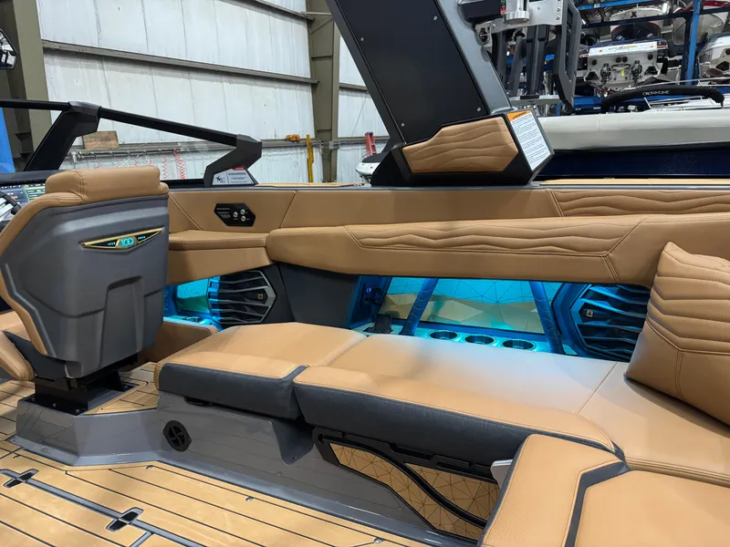 Slide: The Image of 2025 Nautique Super Air Nautique G23 interior with tan leather seating and blue LED lighting. - 12