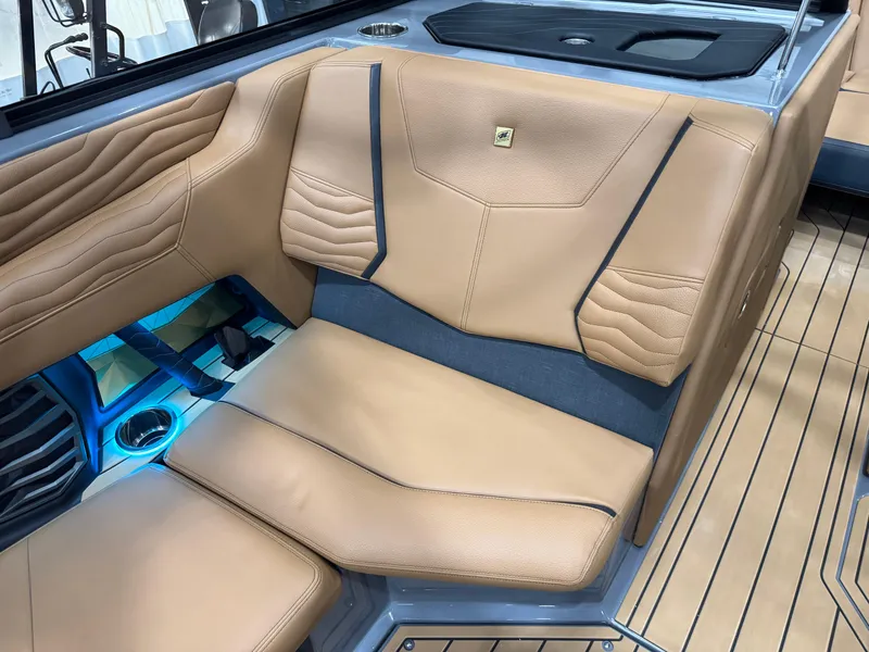 Slide: The Image of 2025 Nautique Super Air Nautique G23 interior with tan leather seating and blue LED lighting. - 16