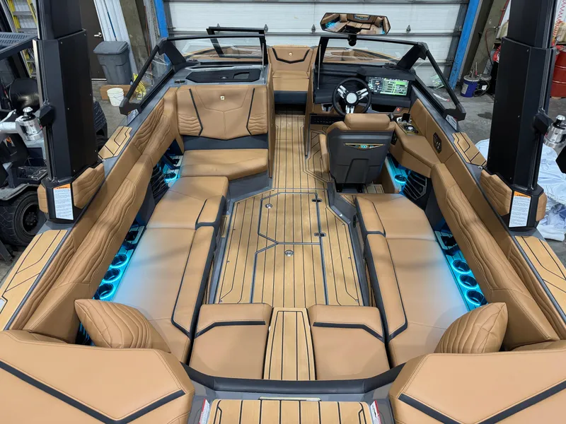 Slide: The Image of 2025 Nautique Super Air Nautique G23 interior with tan upholstery and ambient blue lighting. - 7