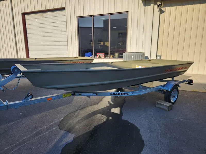 Slide: The Image of 2025 Tracker 1542 LW boat on Load Rite trailer, parked outside a building. - 2